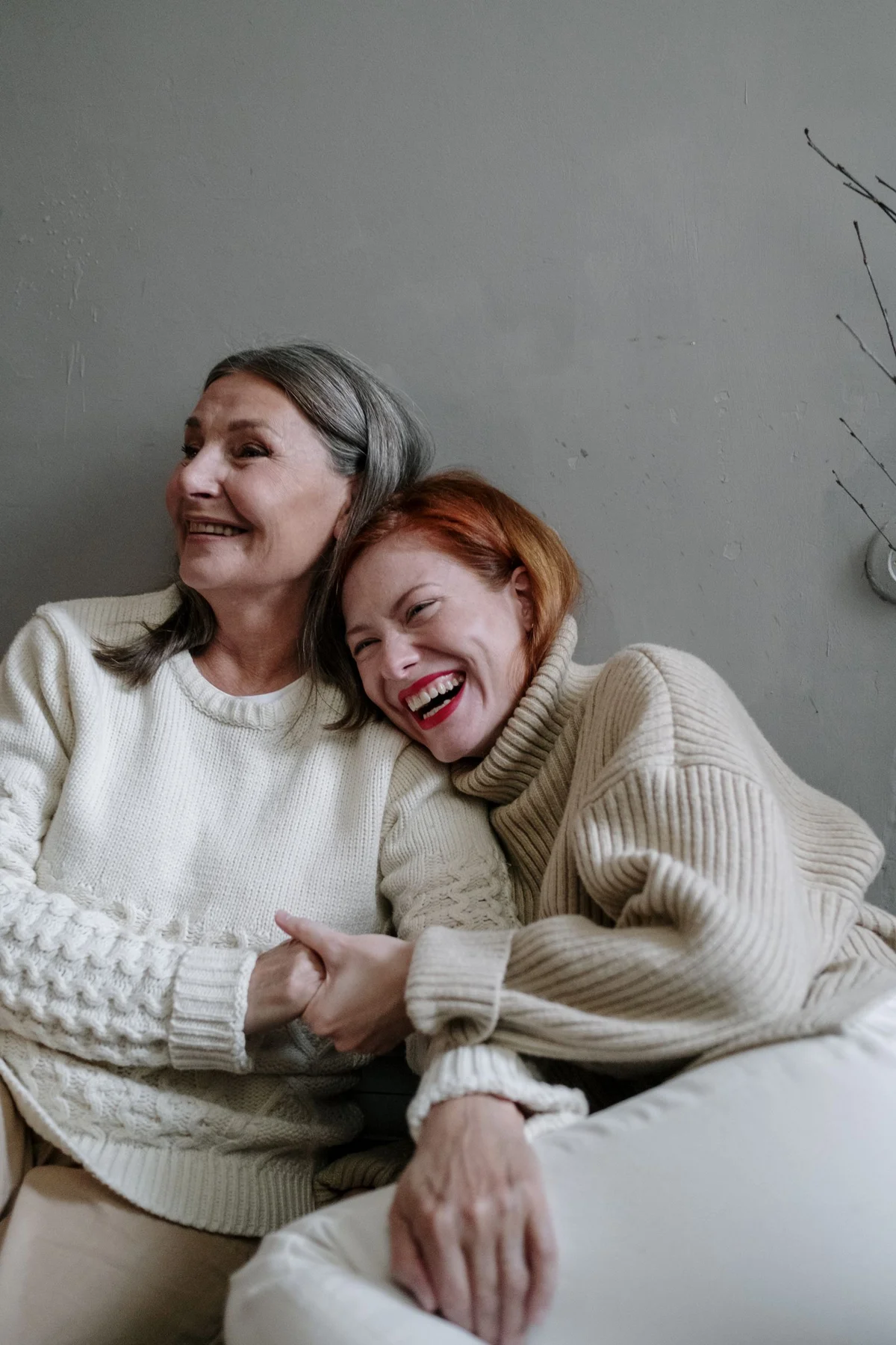 An older mother and her adult daughter sharing a relaxed moment at home